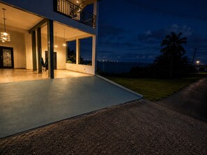 A modern two-story building with a balcony, large windows, and a view of the ocean.