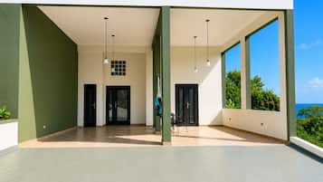 A spacious covered area with two doors, a chair, and hanging lights.