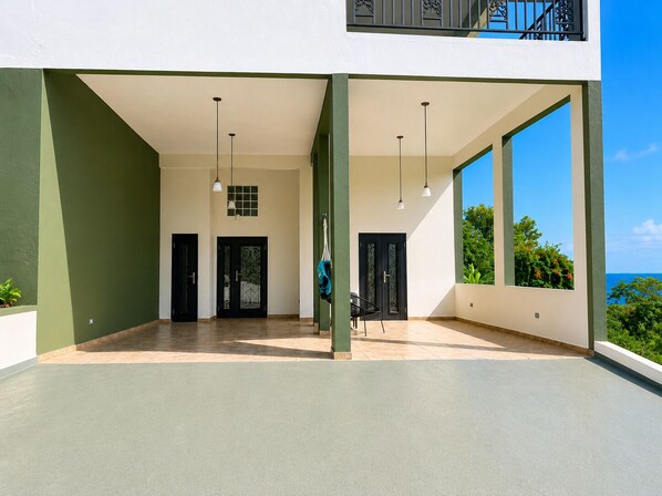 A spacious covered area with two doors, a chair, and hanging lights.