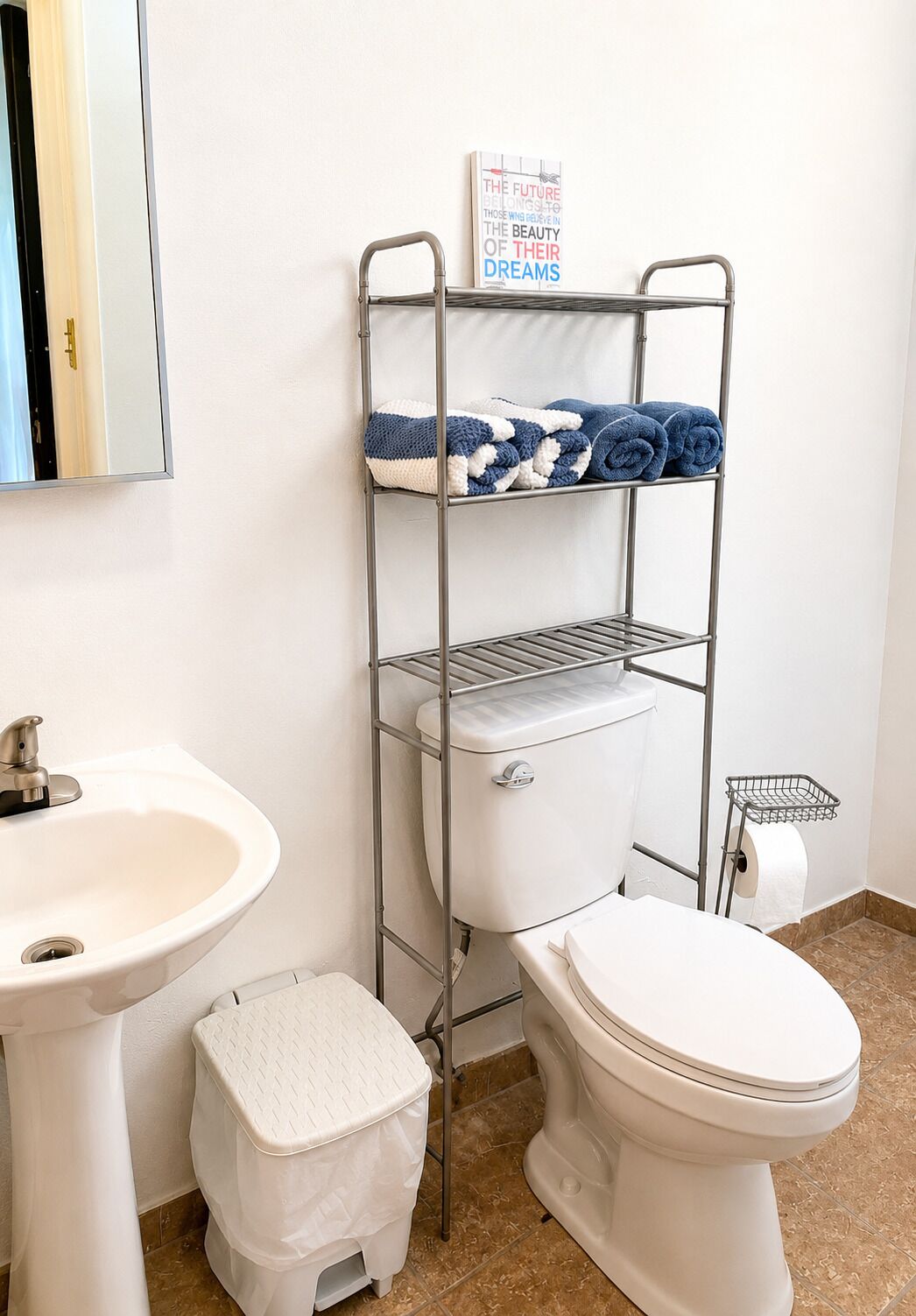 Ein Badezimmer mit Waschbecken, Toilette und einem Metallregal mit Handtüchern.