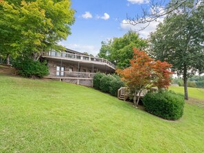 A two-story building with a balcony, surrounded by well-maintained grass and trees. - Decked Out in Dismal - Decks and Amenities! (Arley)