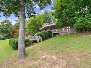 A two-story house with a wooden deck and a staircase leading to the upper level. - Decked Out in Dismal - Decks and Amenities! (Arley)