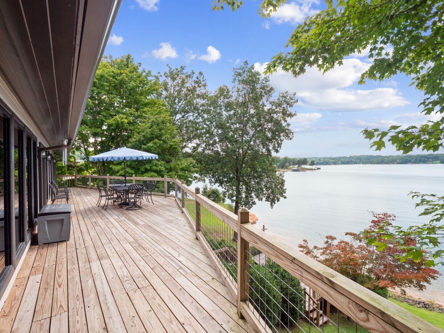 A wooden deck with outdoor furniture and a view of a lake.
