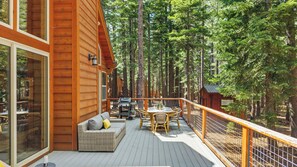 Eine Holzterrasse mit Gartenmöbeln, einem Esstisch und Grillplatz.