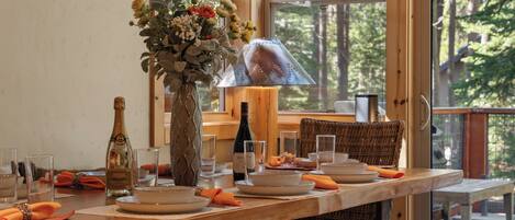 A dining table set with plates, glasses, a bottle, and a vase with flowers.