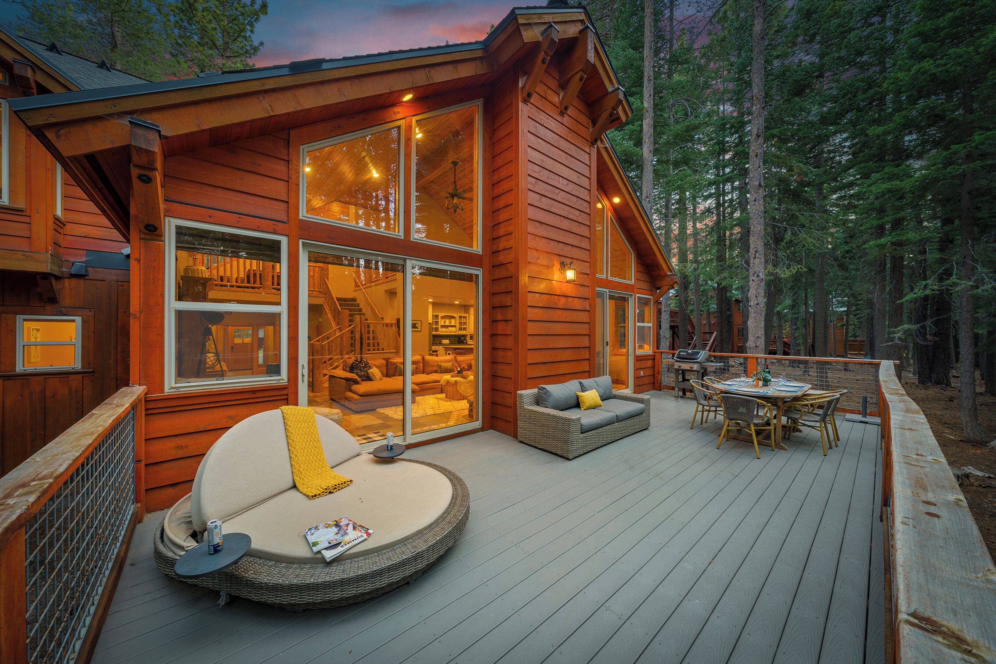 A wooden cabin with a deck, large windows, and a cozy interior.