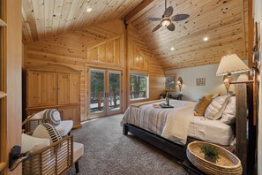 A wooden interior with a bed, a wicker chair, and a large window. - Tahoe Family Lodge | King Suite | Game Loft | Rec Center Access | Near Trails (Truckee)