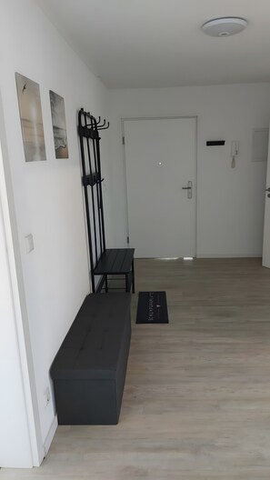 A room with a bench, a coat rack, and a door.