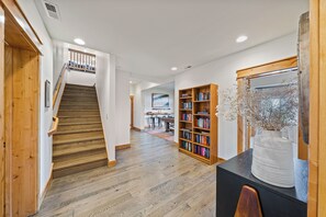 Ein geräumiger Flur mit einer Holztreppe, einem Bücherregal und einem Schreibtisch mit einer Vase.
