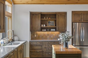 Eine Küche mit Holzschränken, einem Edelstahlkühlschrank und einer Vase mit Grünpflanzen auf der Arbeitsfläche.