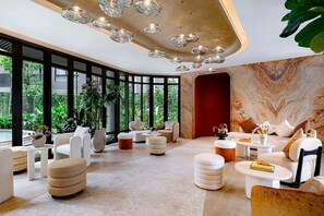 A modern interior with a curved ceiling, multiple seating areas, and large windows offering a view of greenery outside. - Pet-Friendly Phuket Apartment | Pool & Gym (Cherngtalay)