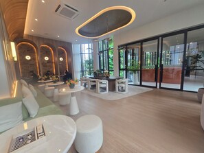 Ein modernes Interieur mit Sitzbereichen, Tischen und großen Fenstern.