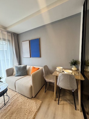 Ein modernes Wohnzimmer mit einer Couch, Sesseln, einem Esstisch und einer kleinen Pflanze.