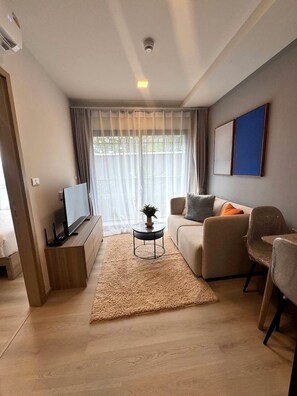 Ein modernes Wohnzimmer mit Flachbildfernseher, einer Couch, einem Couchtisch und einem Teppich.