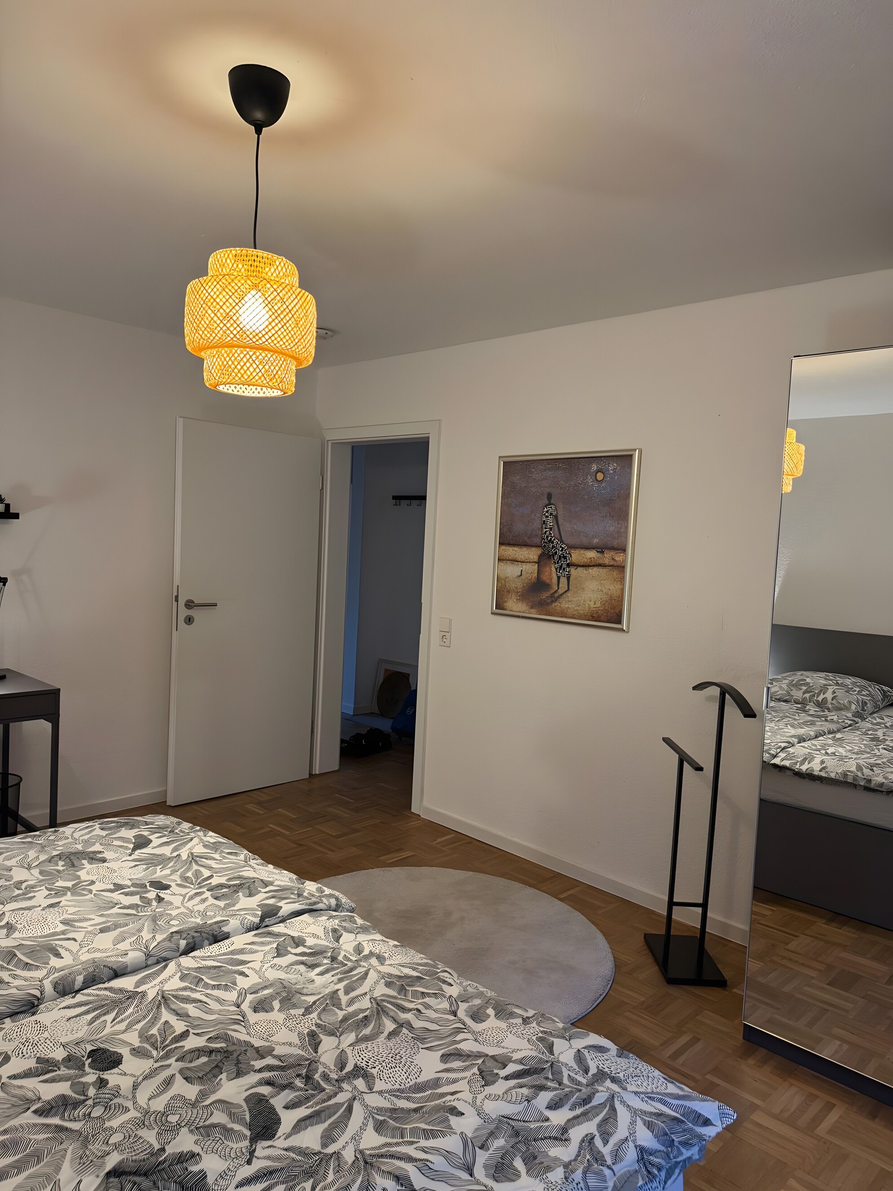 Et soveværelse med en seng, en gulvlampe, et maleri og en køjeseng.