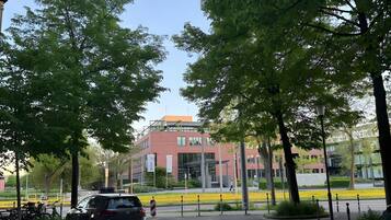 Un espace de stationnement avec des voitures, des arbres et un bâtiment à la façade rouge.