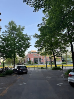 Ein Parkplatz mit Autos, Bäumen und einem Gebäude mit roter Fassade.