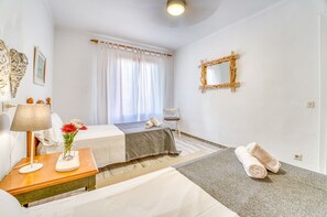 A hotel room with a bed, a bedside table with a lamp, a chair, a mirror, and towels on the floor. - House with garden Can Nofre in Playa de Muro (Muro)