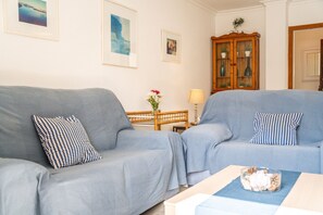 En stue med to grå sofaer, et træskab med glasdøre og et lille bord med en vase blomster.
