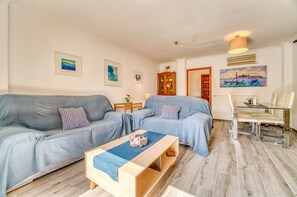 A living room with a grey sofa, a wooden coffee table, and a glass dining table with chairs. - House with garden Can Nofre in Playa de Muro (Muro)