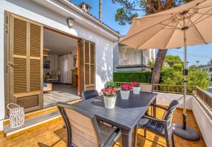An outdoor patio with a table and chairs, a beige umbrella, and potted plants. - House with garden Can Nofre in Playa de Muro (Muro)