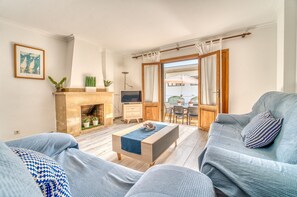 Una sala de estar con chimenea, televisor y comedor con mobiliario para exteriores.