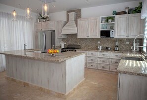 A modern kitchen with a large island, stainless steel appliances, and a granite countertop. - Your Dream Family or Group Getaway: 5 Bedroom Luxury Villa Awaits in Cofresi! (Cofresi)