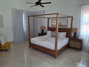 A four-poster bed with a wooden frame, a nightstand with a lamp, and a bedside table with a phone and a bottle. - Your Dream Family or Group Getaway: 5 Bedroom Luxury Villa Awaits in Cofresi! (Cofresi)