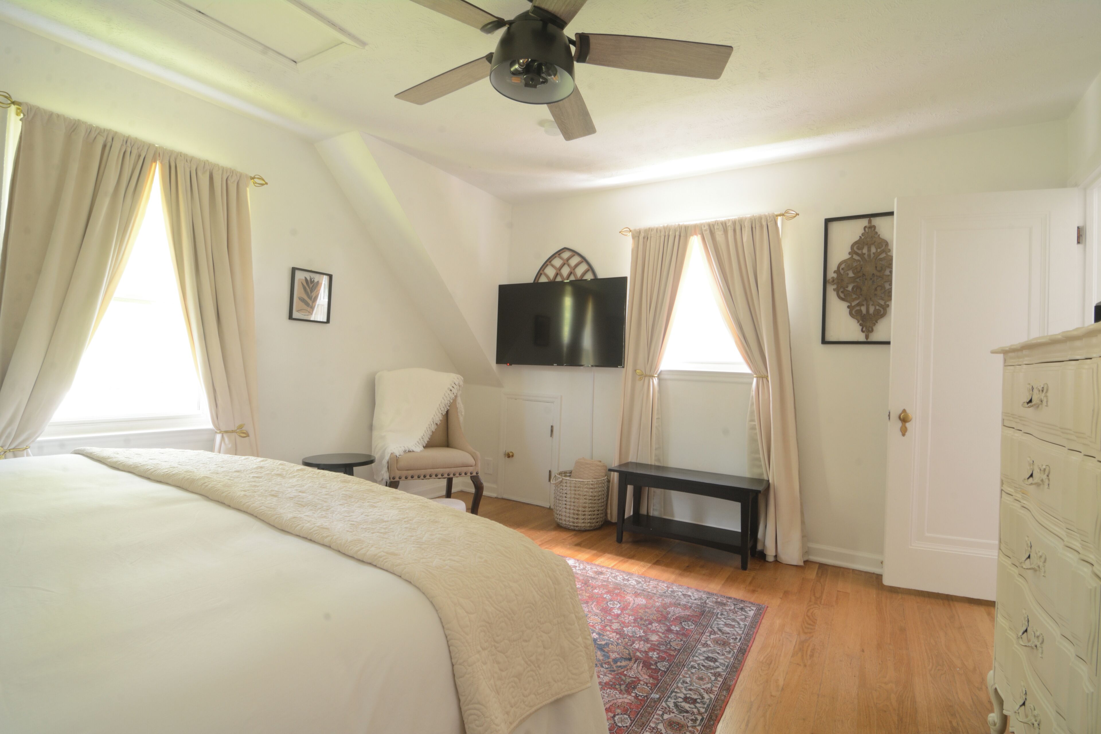 Une chambre à coucher avec un lit, une chaise, une télévision et une commode.