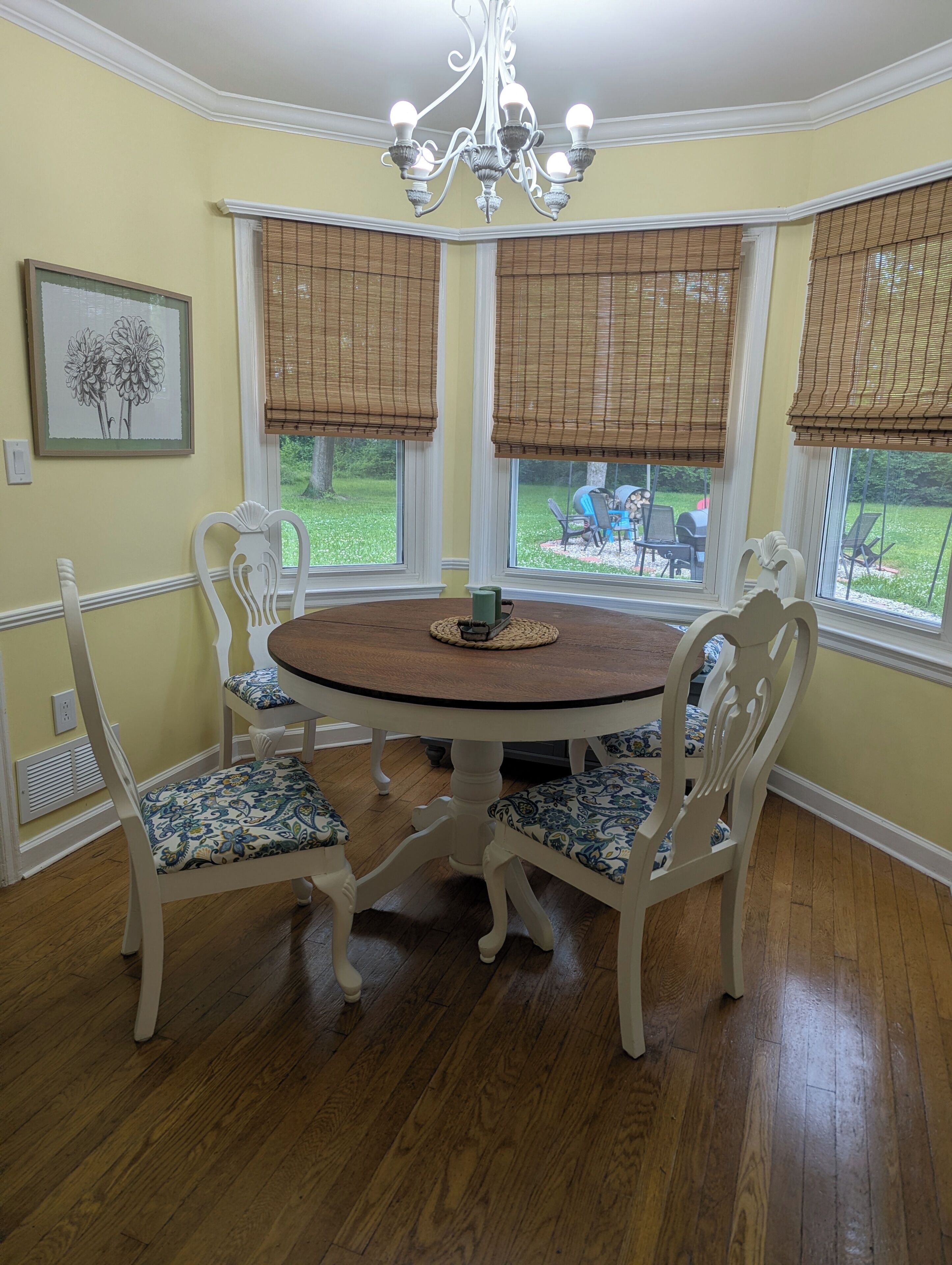 A dining area with a round table, white chairs, and a chandelier.