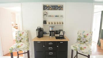 Eine kleine Küchenzeile mit Kaffeemaschine, Wasserkocher und Stauraumschränken.