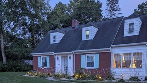 A two-story house with a front porch, a brick facade, and a sloped roof.