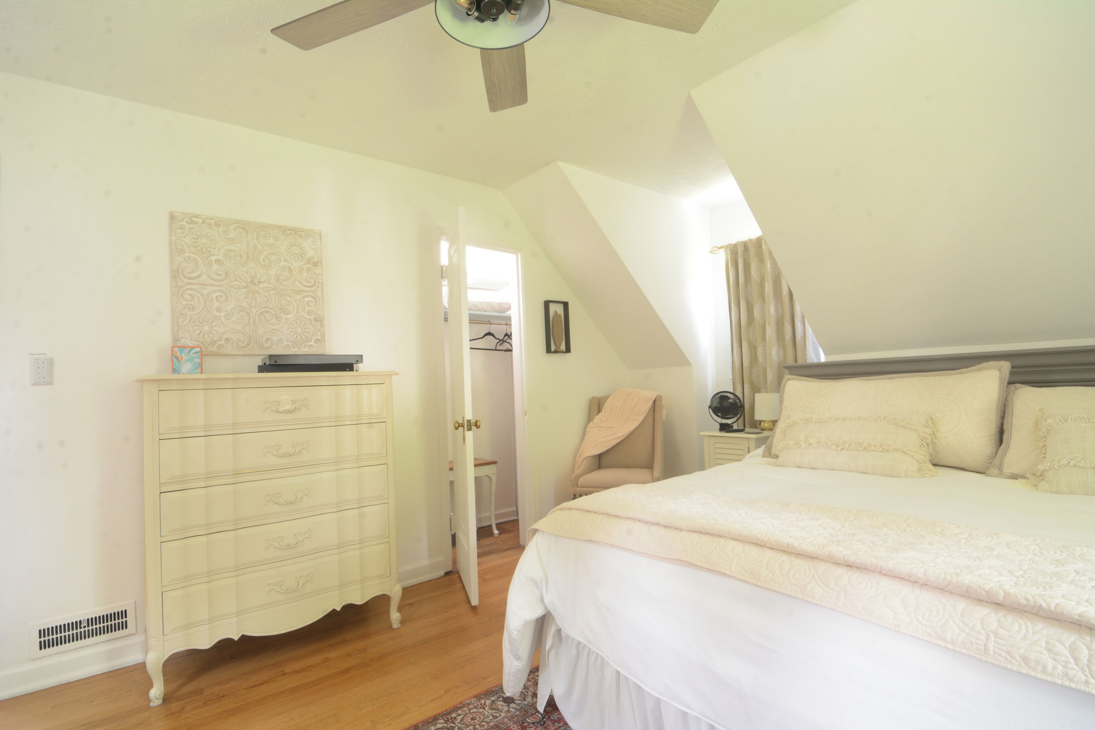 Une chambre à coucher avec un lit, une commode et un ventilateur de plafond.