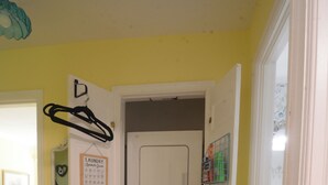 A compact laundry room with a washer and dryer, a hanging rack, and a laundry symbols guide on the wall.