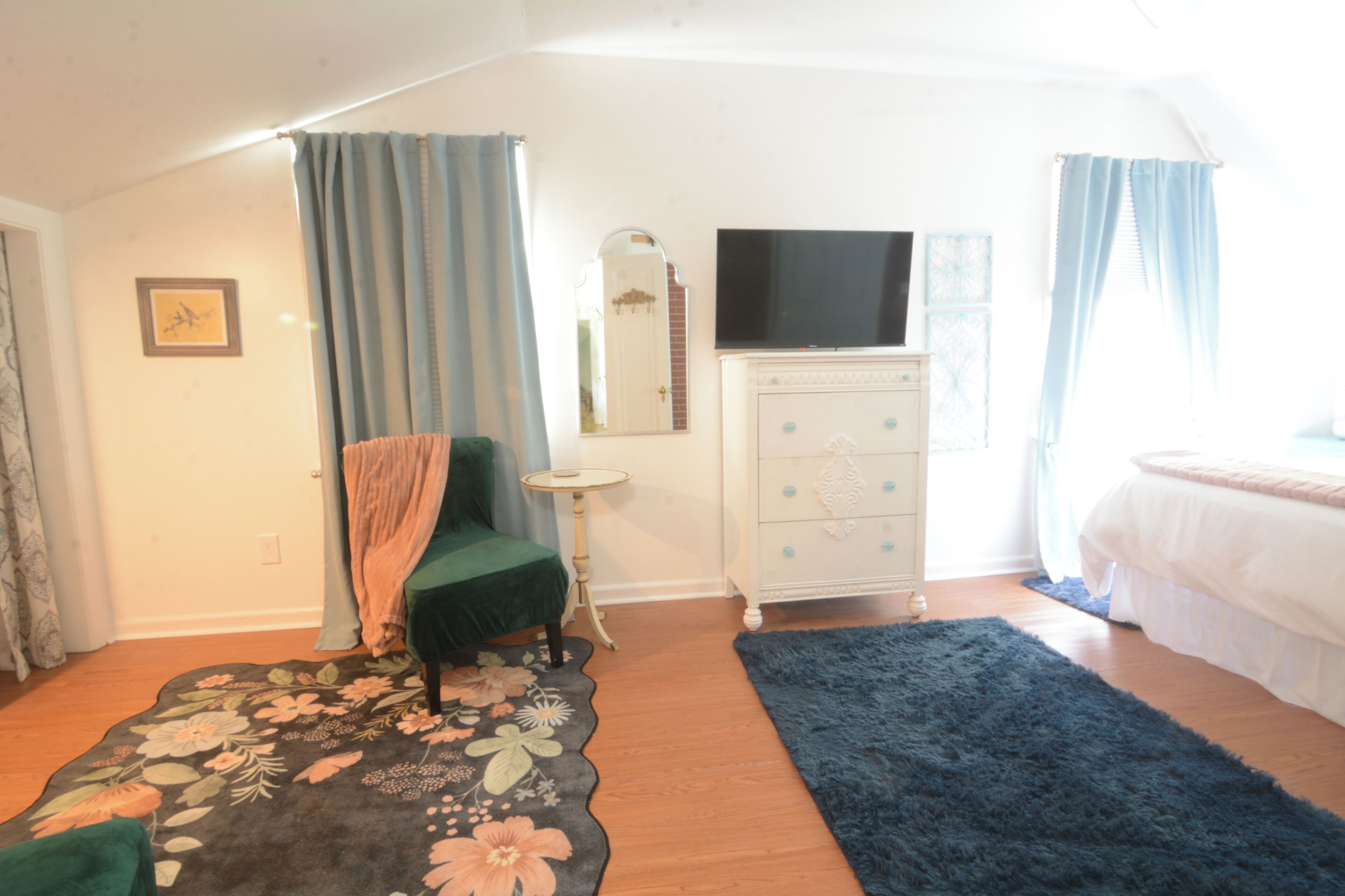 Ein Schlafzimmer mit Bett, Schminktisch, Fernseher und Stuhl.