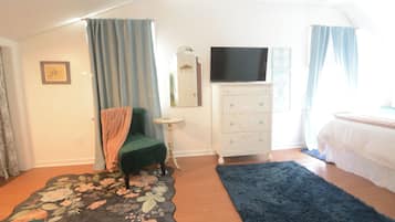 Ein Schlafzimmer mit Bett, Schminktisch, Fernseher und Stuhl.