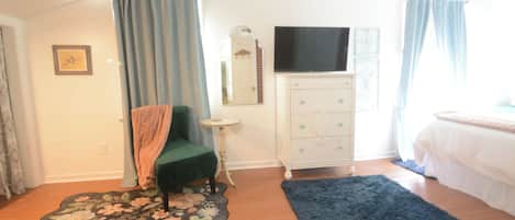 Un dormitorio con cama, cómoda, televisor y una silla.
