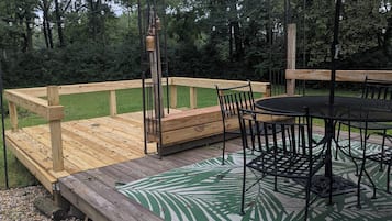 Eine Holzterrasse mit Tisch und Stühlen, umgeben von einem Holenzaun und Grünpflanzen.
