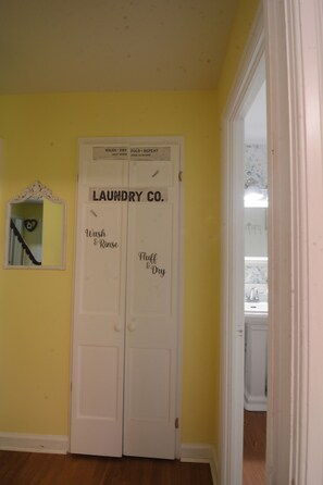 A laundry room with a sign indicating self-service wash and dry facilities, open 24 hours.
