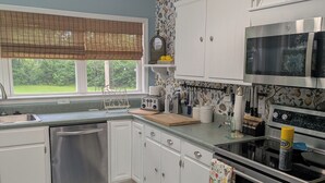 A kitchen with white cabinets, stainless steel appliances, a window with a view, and a patterned floor.