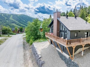 Et moderne hus med træterrasse, store vinduer og udsigt til et bjerg.