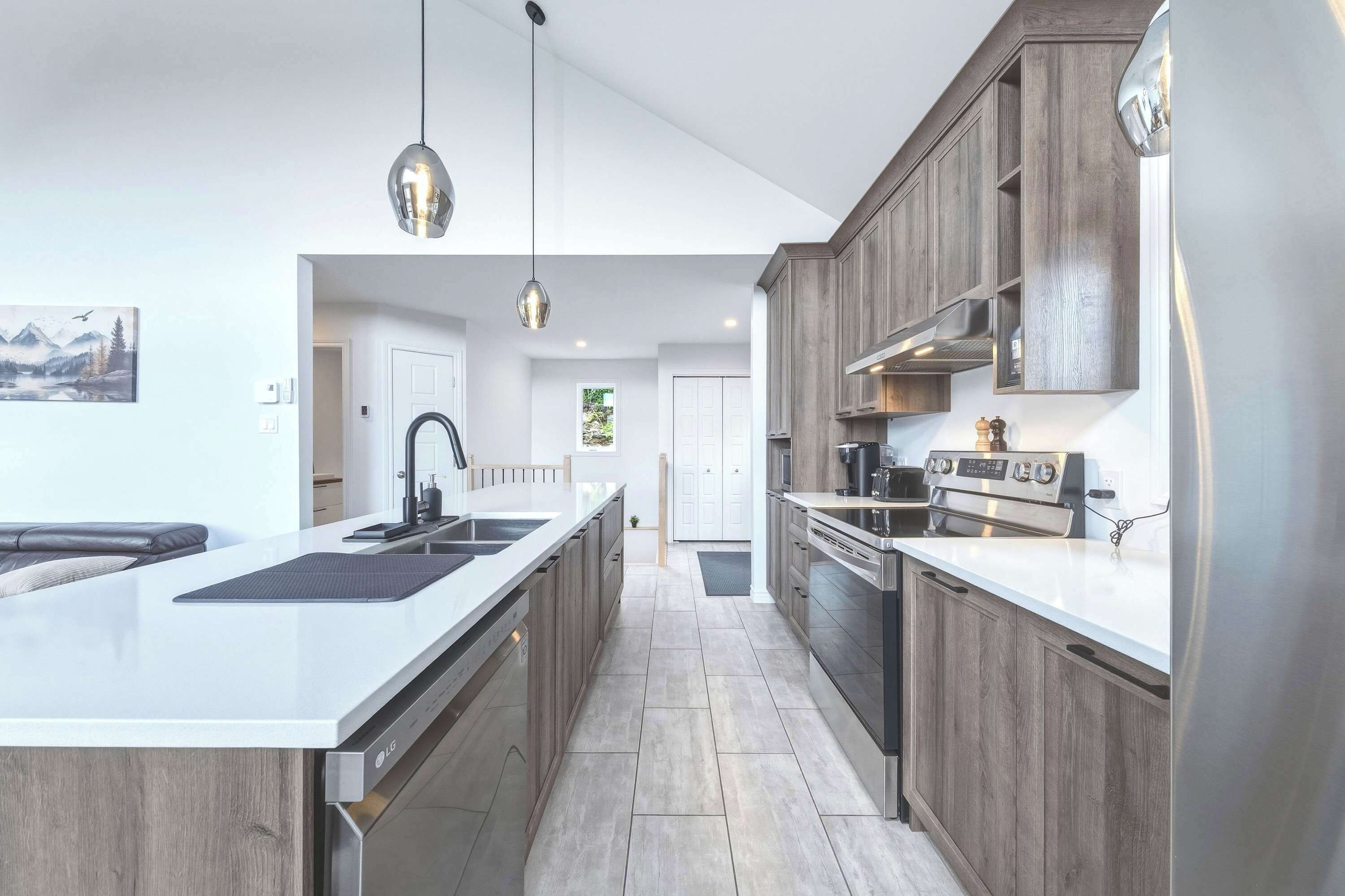 A modern kitchen with a central island, stainless steel appliances, and wooden cabinetry.