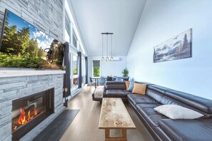 Un salon moderne avec une cheminée, un canapé, une table basse et un tableau au mur.