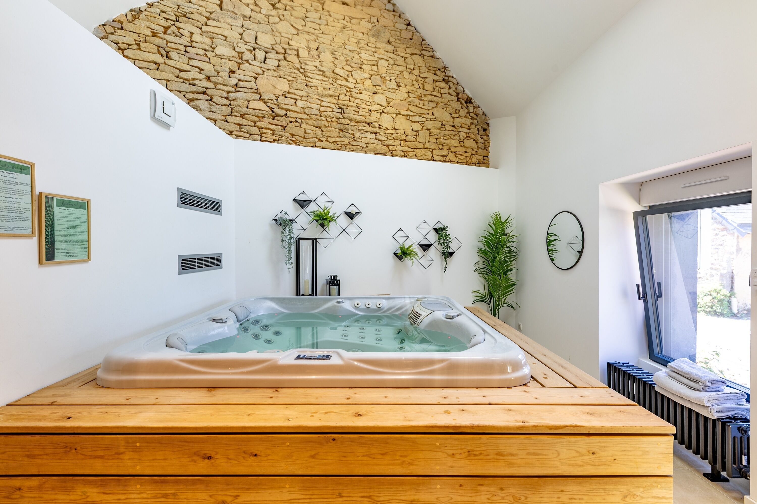 Une salle de bain moderne avec un mur en pierre, une baignoire sur pieds et un banc en bois.