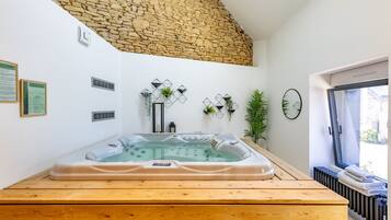 Une salle de bain moderne avec un mur en pierre, une baignoire sur pieds et un banc en bois.