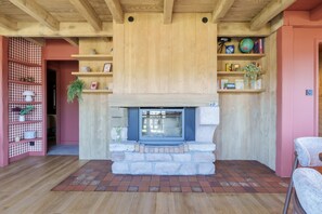 Ein gemütliches Wohnzimmer mit Kamin aus Stein, Holzbalken und einer rauen Regalwand.