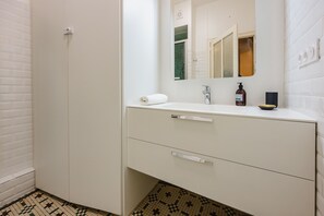 Ein Badezimmer mit einem weißen Waschbecken, einem Spiegel, einem Handtuch und einer Shampooflasche.