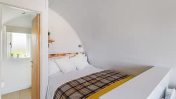 A bedroom with a bed, a bedside table, a window, and a door.