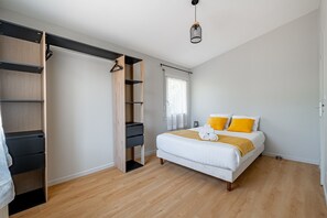 Ein Schlafzimmer mit Bett, Kleiderschrank und einer Pendelleuchte.