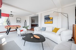 Een moderne woonkamer met een bank, bijzettafeltje en een pooltafel.